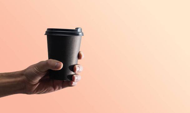Ruka drží hrnek, papírový šálek kávy s lahodnou kávou v kavárně na pozadí, maketa up, prázdný, vaše kavárna shop design - Fotografie, Obrázek