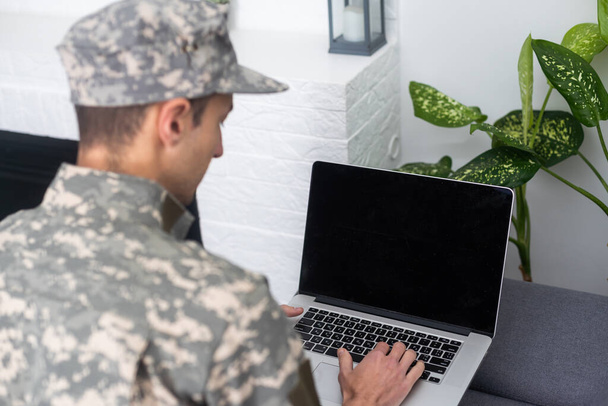 Soldat in Uniform schaut auf Laptop. - Foto, Bild