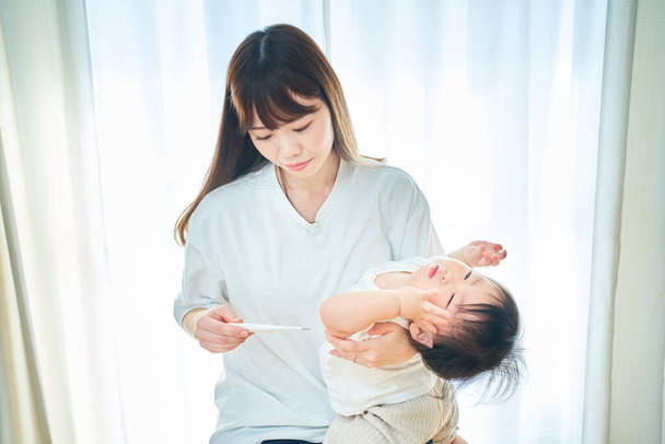 Un niño pequeño teniendo a su madre midiendo su temperatura - Foto, Imagen
