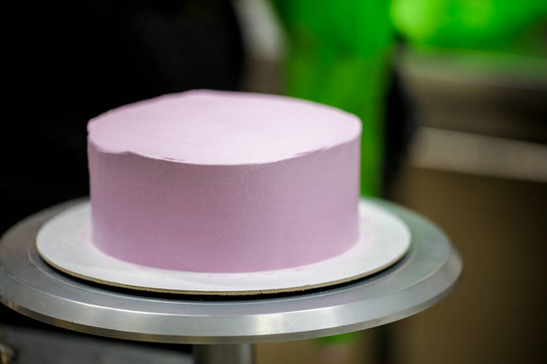 cukiernik za pomocą szpatułki skrobak do wygładzenia liliowy różowy masło lukier ciasto - tort urodzinowy przygotowanie - Zdjęcie, obraz