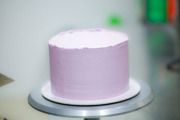 cukrász spatulával és kaparóval simító réteges lila vajkrém cukormázas torta - esküvői torta elkészítése - Fotó, kép