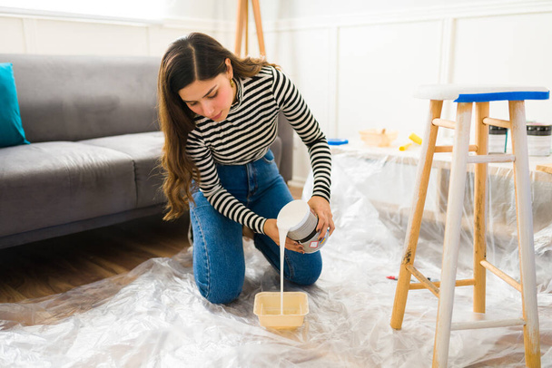 Mujer hispana preparando pintura para comenzar su proyecto de renovación de muebles en casa - Foto, Imagen