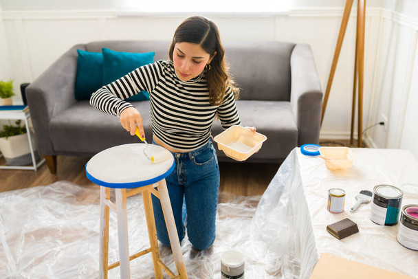Beautiful woman painting her furniture and doing a home improvement restoration project or hobby - Photo, Image