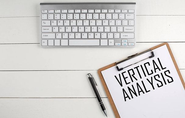 Домашній офіс робочий простір з клавіатурою, буфера і ручкою з текстом VERTICAL ANALYSIS на білому дерев'яному фоні, бізнес-концепція
 - Фото, зображення
