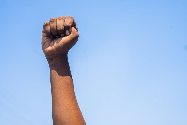 Concept van de zwarte geschiedenis maand viering of activist Hand opstaan tegen de hemel tijdens maart tonen met kopieerruimte. - Foto, afbeelding