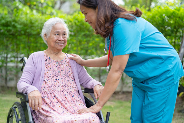 Opiekun lekarz pomoc i opieka azjatycki seniora lub starsza pani pacjentka siedzi na wózku inwalidzkim w parku w szpitalu pielęgniarskim, zdrowe silnej koncepcji medycznej - Zdjęcie, obraz