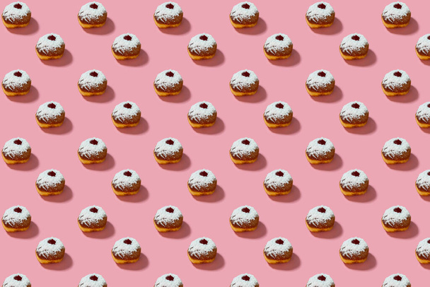 Jewish holiday Hanukkah concept. Pattern with donut sufganiyot on a pink background. - Фото, изображение