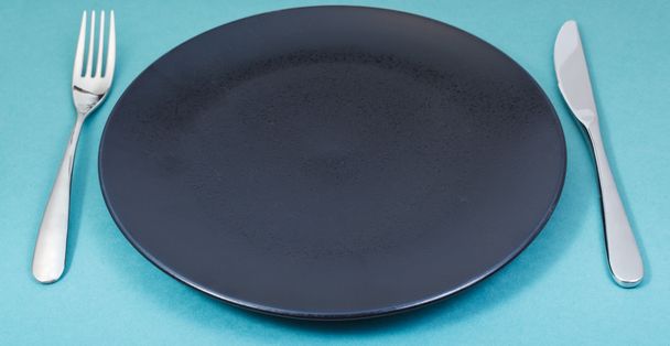 assiette noire dîner avec fourchette et couteau sur vert
 - Photo, image
