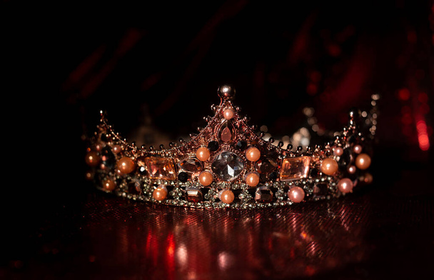 Magiczna korona z cennymi klejnotami na czerwonym, luksusowym tle tkaniny - Zdjęcie, obraz