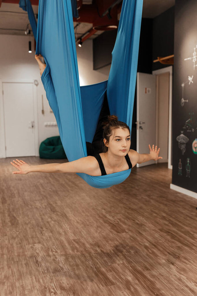 Bella ragazza bruna è impegnata in fly yoga in studio - Foto, immagini