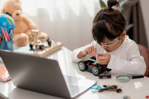 Aziëstudenten leren thuis in het coderen van robotauto 's en elektronische kartonnen kabels in STEM, STEAM, wiskunde engineering science technology computer code in robotica voor kinderen concept. - Foto, afbeelding