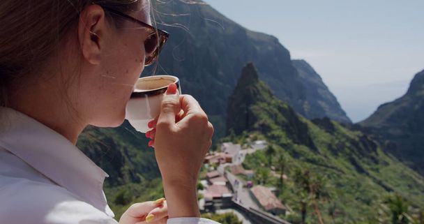 Masca Gorge. Young woman drinks coffee enjoying the landscape. Tenerife, Canary Islands, Spain. - Фото, изображение