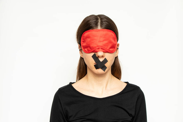 A girl with a blindfold and a closed mouth with a band-aid on an isolated background, a blind and dumb girl - Fotó, kép
