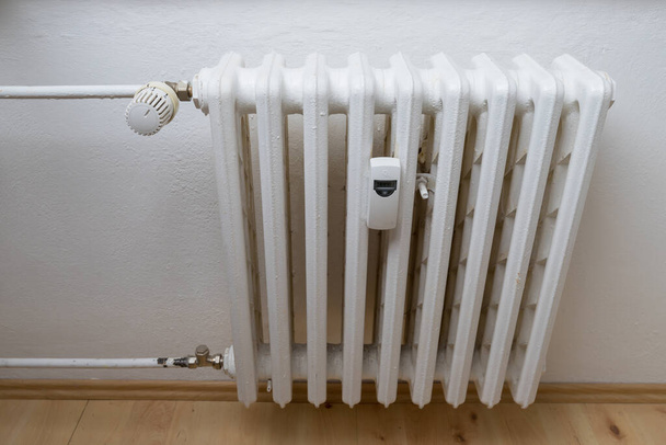 Radiador de calefacción con medidor de calor y válvula para regulación. - Foto, imagen