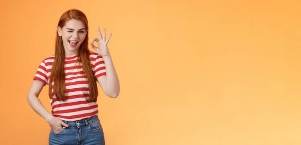 Sassy stylish sly redhead cheerful girl assuring everything excellent, show okay sign and wink cheeky, accept awesome idea, approve good job, express satifaction from positive result, like choice. - Photo, Image