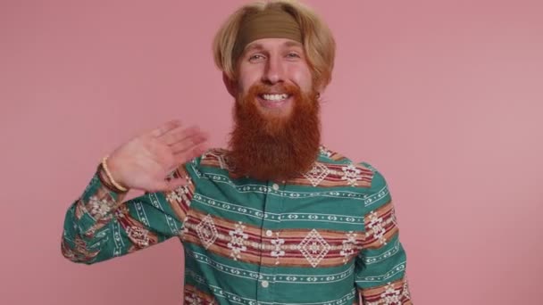 Come here, join us. Welcome. Handsome bearded hippie man showing inviting gesture with hands, ask to join, beckoning to coming, gesturing hello or goodbye. Young hipster guy boy on pink background - Footage, Video
