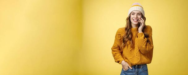 Carefree sociable good-looking outgoing woman calling friend talking happily smartphone have pleasant funny conversation smiling giggling look away hold hand pocket, standing yellow background. - Photo, Image