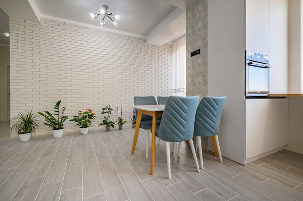 Nowoczesny modny biały apartament typu studio ze stołem jadalnym i rzędem zielonych roślin, dużo miejsca do kopiowania - Zdjęcie, obraz