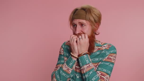 Upset scared frightened hippie redhead bearded man biting nails, feeling worried nervous about serious troubles, stress, anxiety disorder, panic attack, guilty. Hipster ginger guy on pink background - Footage, Video