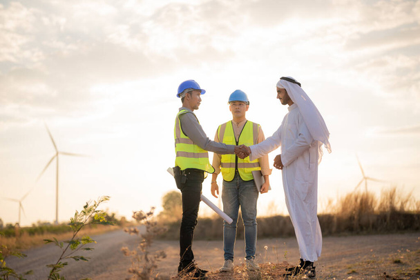 Ázsiai mérnökök és arab üzletember ellenőrzi és ellenőrzi az építőipar naplemente ég. Emberek operálnak. Szélturbina elektromos tiszta energia és a környezet. Fenntartható ipar. - Fotó, kép