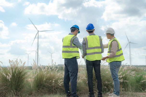Asian engineer working in fieldwork outdoor. Workers check and inspect construction and machine around building project site. Wind turbine for electrical of clean energy and environment sustainable. - Photo, Image