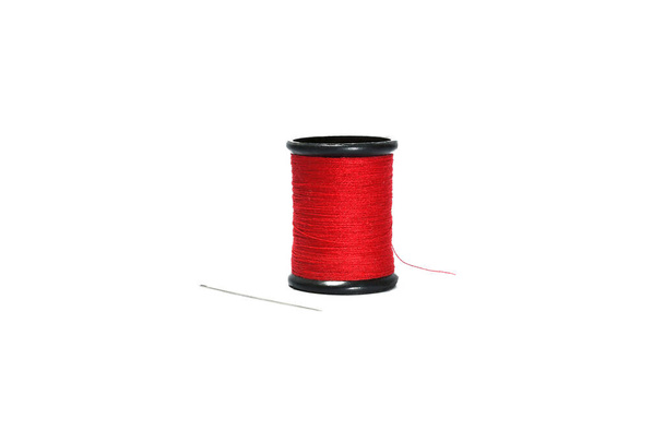 Rood naaigaren in zwart haspel met naainaald geïsoleerd op witte ondergrond. - Foto, afbeelding
