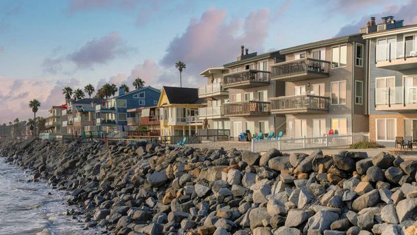 Günbatımında Panorama Puffy bulutları Oceanside, California 'nın kıyı bölgesinde yerleşim binaları. Modern ve geleneksel tasarımları olan çok katlı binaların solunda deniz manzarası var.. - Fotoğraf, Görsel
