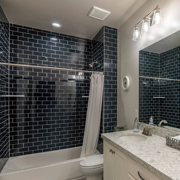 Square Master fürdőszoba dupla hiúság mosogató és zuhanyzó kád fekete metró csempe körül. A fürdőszoba belseje törölközőkkel a tálcán a gránit pult tetején, a falitükör közelében. - Fotó, kép