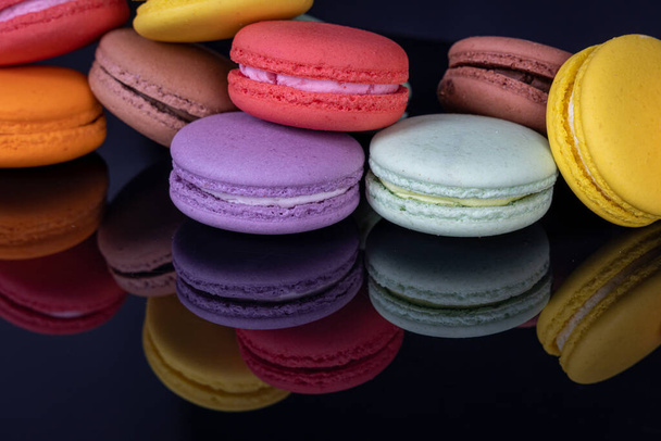 Veel kleurrijke macarons op zwarte achtergrond met reflectie. Traditioneel Frans dessert - Foto, afbeelding