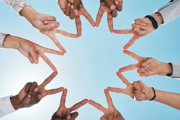 Team building, blue sky or hands with peace sign for support, teamwork or partnership collaboration. Low angle, trust or fingers showing hope, faith or community group solidarity with mission goals. - Photo, Image
