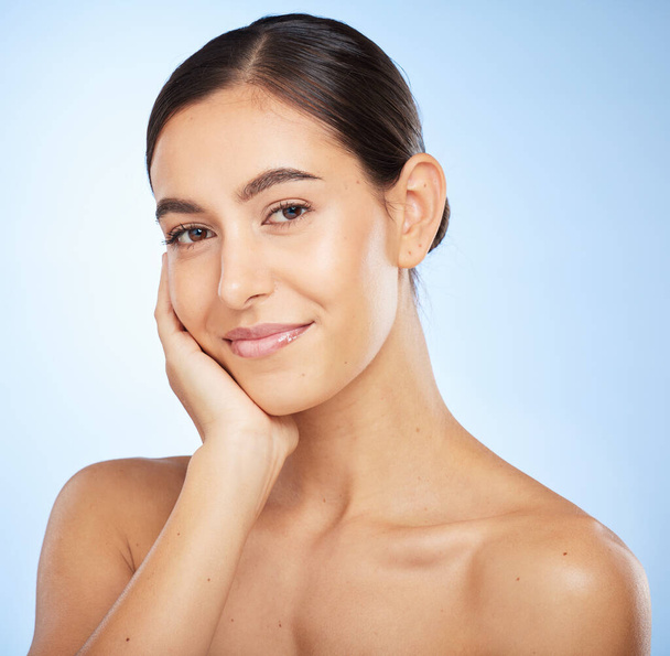 Portrait, skincare and beauty with a model woman in studio on a blue background for natural treatment. Face, wellness and luxury with an attractive young female posing to promote a skin care product. - Photo, Image