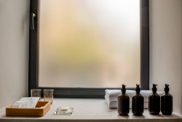 bottles with bathroom accessories near fresh towels in hotel  - Foto, Imagen