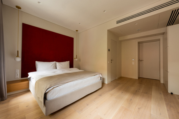 άνετο κρεβάτι με λευκά μαξιλάρια σε μοντέρνο δωμάτιο ξενοδοχείου  - Φωτογραφία, εικόνα