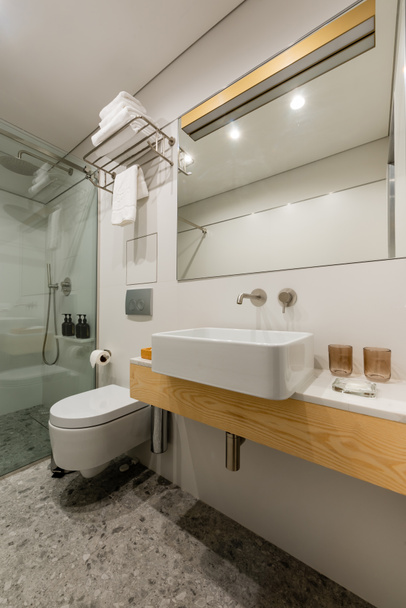 интерьер современной ванной комнаты с белыми чистыми стаканами возле раковины - Фото, изображение