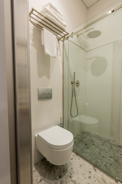 ガラスのドアの近くに白いトイレとシャワー付きのモダンな白いバスルームのインテリア  - 写真・画像
