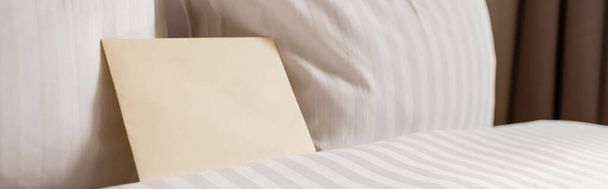 ホテルの部屋に白ときれいな寝具の上の空白の封筒、バナー  - 写真・画像