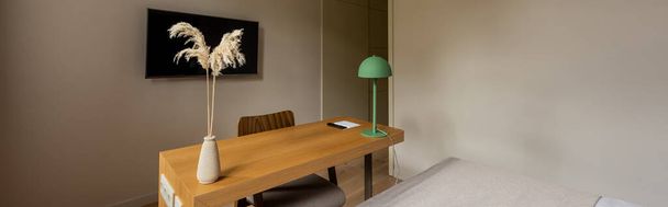 wooden desk and tv with blank screen on wall near bed in room of hotel, banner  - Photo, Image
