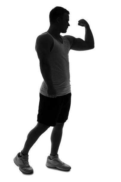 Silhouette of sporty young man showing muscles on white background - Photo, Image