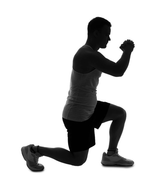 Silueta sportovního mladého muže cvičení na bílém pozadí - Fotografie, Obrázek