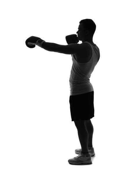 Silhouette of sporty young man in boxing gloves on white background - Photo, Image