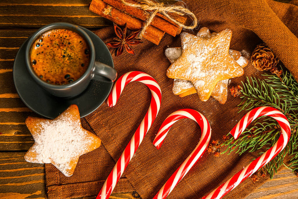 Σύνθεση με νόστιμες καραμέλες, χριστουγεννιάτικα μπισκότα και φλιτζάνι καφέ σε ξύλινο τραπέζι, closeup - Φωτογραφία, εικόνα