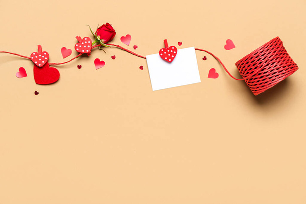 Touw met blanco kaart, roos en hartjes op beige achtergrond. Valentijnsdag - Foto, afbeelding