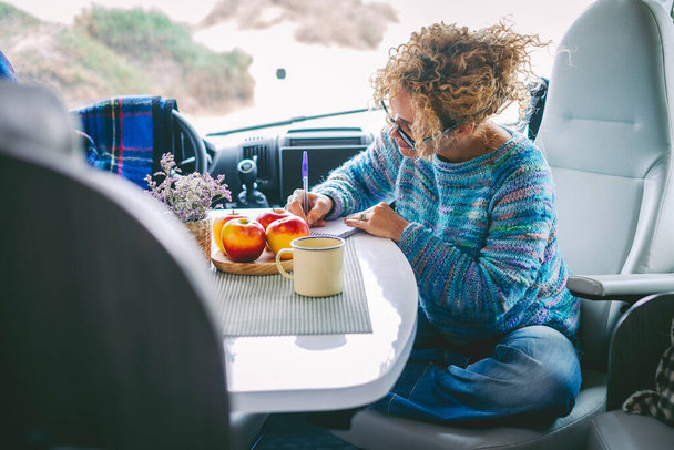 Cestování marihuany životní styl lidí koncept. Jedna žena snídala a psala mapy na výlet, jak sedí sama v kabině moderního obytného přívěsu karavanu. Myšlenka cestovatelky a svobody - Fotografie, Obrázek
