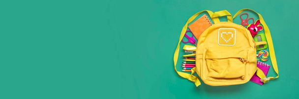 Back to school, education concept Yellow backpack with school supplies - notebook, pens, eraser rainbow, numbers isolated on green background Top view Copy space Flat lay composition Banner. - Photo, Image