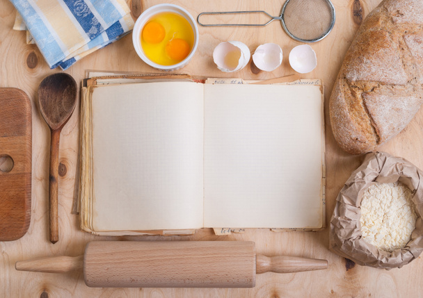 Fondo para hornear con libro de cocina en blanco, cáscara de huevo, harina, balanceo
 - Foto, imagen