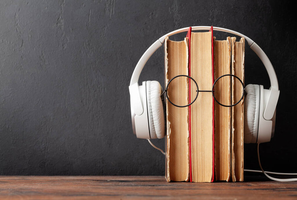 Staré knihy, sluchátka a brýle na dřevěném stole a tabuli pro kopírování prostoru. Audiobooks a vzdělávací šablona - Fotografie, Obrázek
