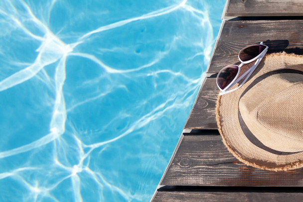Sunglasses and sunhat near swimming pool. Summer vacation. Flat lay with copy space - Photo, Image