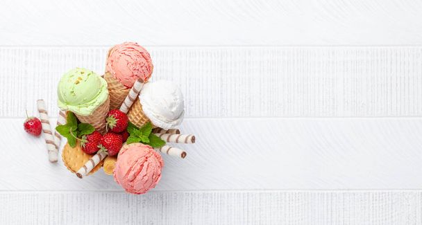 ワッフルコーンの中の様々なアイスクリーム。ストロベリー、ピスタチオ、バニラアイス。コピースペース付きフラットレイアウト - 写真・画像