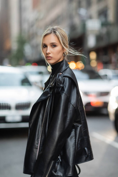 Портрет блондинки в стильній шкіряній куртці, яка дивиться на камеру на міській вулиці в Нью-Йорку. - Фото, зображення