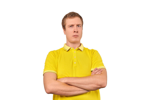 Suspicious guy crossed arms on his chest, proud look isolated on white background. Young doubtful man in yellow T-shirt with crossed arms, gesture of defensiveness, body language - Fotografie, Obrázek